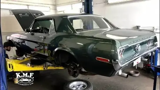 Vintage green Ford Mustang on a lift at KMF Automotive, illustrating reliable auto repair near me services.