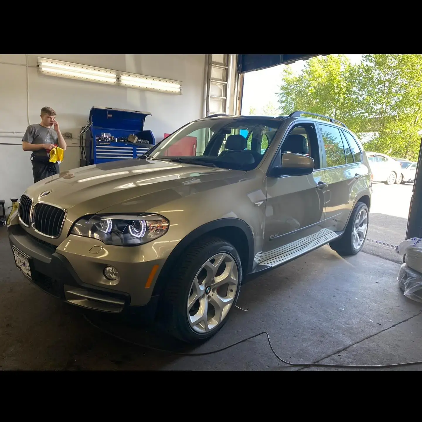 BMW X5 SUV in a car repair shop with technician working, showcasing the possibility of same-day car repair services – Can I Get Car Repair Done Today?
