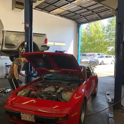 Affordable Auto Repair Near Me – mechanic inspecting engine of a red sports car inside a professional auto repair shop with vehicle on lift in background